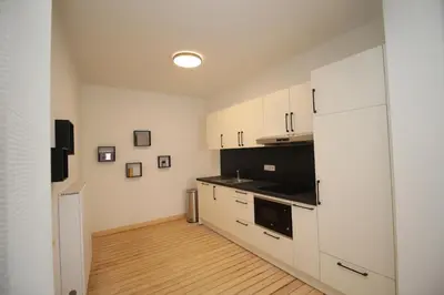 a kitchen with white cabinets and a black appliance at Appart Nicolas in Eupen