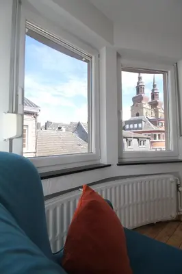 a living room with two windows and a blue couch at Appart Nicolas in Eupen