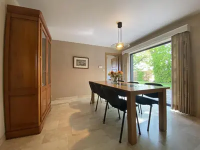 a dining room with a table and chairs and a window at Drieskenshoeve in Grote-Brogel