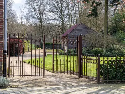an iron fence with a gate in a park at De Kievelder in Peer