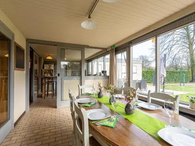a dining room with a wooden table with white chairs at Het Bruegelhof in Peer