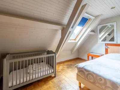a bedroom with a crib in a attic at Het Bruegelhof in Peer
