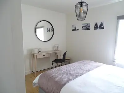 a bedroom with a bed and a desk and a mirror at Vakantiewoning Mèzik in Maasmechelen