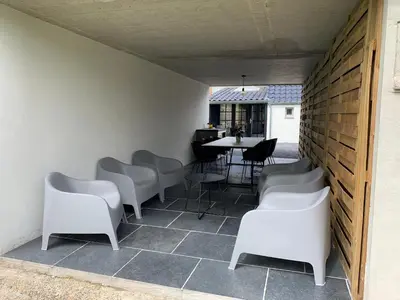 a patio with white chairs and a table at Vakantiewoning Mèzik in Maasmechelen