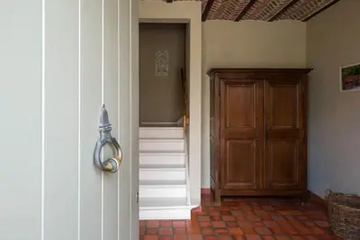 a hallway with a staircase and a wooden door at Glabbeek-hoeve in Geetbets