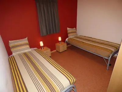 two twin beds in a room with red walls at De Alpacaboerderij in Bocholt