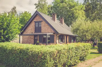 a brick house with a roof on top of a hedge at Landhuisjes Bij De Wouterbron in Oudsbergen