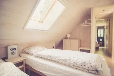 a attic bedroom with a bed and a window at Landhuisjes Bij De Wouterbron in Oudsbergen