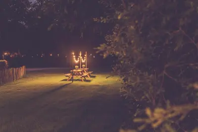 a picnic table with lights in a field at night at Landhuisjes Bij De Wouterbron in Oudsbergen
