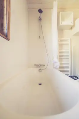 a bath tub with a shower in a room at Landhuisjes Bij De Wouterbron in Oudsbergen