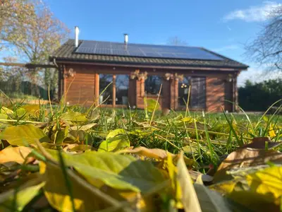 a log cabin with a field of grass in front of it at Nîdwazô - Ecolodge & Maison d'hôtes in Trooz