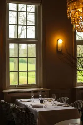a dining room with a table and two windows at Landgoed Altenbroek in Voeren