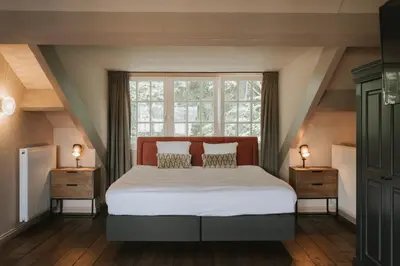 a bedroom with a large bed with two night stands at Landgoed Altenbroek in Voeren