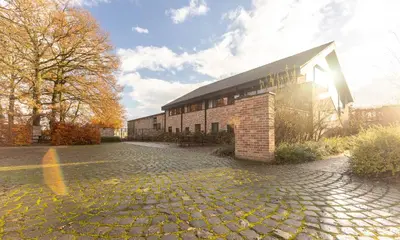 a brick building with the sun shining behind it at De Zwaluwhoeve in Peer