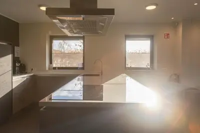 a kitchen with a white counter and two windows at De Zwaluwhoeve in Peer