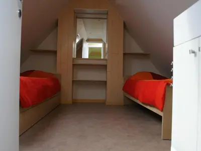a attic bedroom with two beds and a mirror at Holiday Home Op 't Busselen in Opoeteren