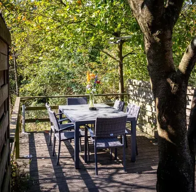 a table and chairs on a deck with a tree at Holiday Home Op 't Busselen in Opoeteren