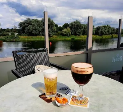 a table with a glass of beer and food on a balcony at Viva La Vie in Maaseik