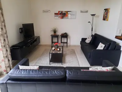 a living room with a black couch and a tv at Hof van Eggertingen nr. 8 in Riemst