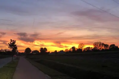 a sunset over a field with a road at Hof van Eggertingen Bakhuis in Riemst