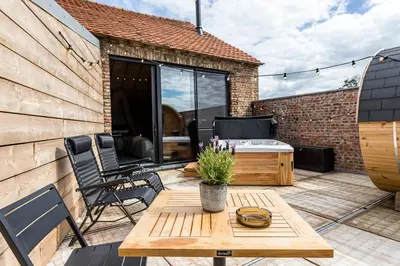 a patio with a wooden table and chairs on a deck at De Hoeveschuur in Riemst