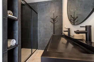a black bathroom with a sink and a mirror at De Hoeveschuur in Riemst