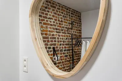 a mirror in a bathroom with a brick wall at De Hoeveschuur in Riemst