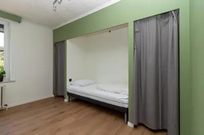 a bed in a room with green and white walls at Vakantiehuis Salamander Maasmechelen in Maasmechelen