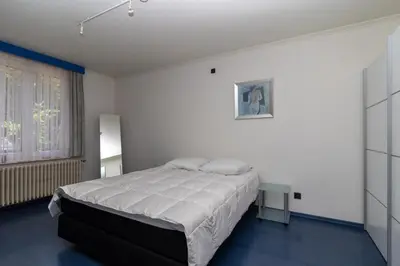a white bedroom with a bed and a window at Vakantiehuis Salamander Maasmechelen in Maasmechelen