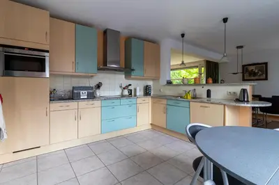 a kitchen with blue cabinets and a table at Vakantiehuis Salamander Maasmechelen in Maasmechelen