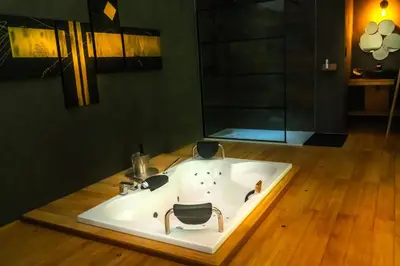 a bathroom with a tub with two chairs in it at Paradis Secret in Beyne-Heusay