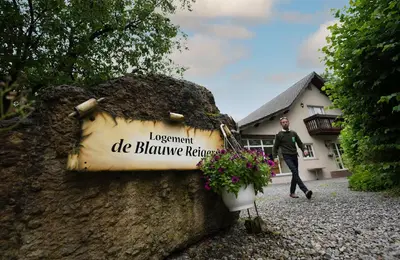 a man walking past a sign on a wall at Logement de Blauwe Reiger in Voeren