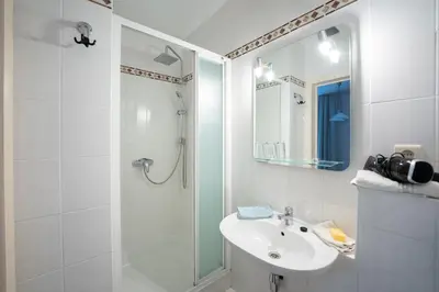 a white bathroom with a sink and a shower at Logement de Blauwe Reiger in Voeren