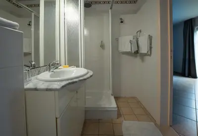 a white bathroom with a sink and a shower at Logement de Blauwe Reiger in Voeren