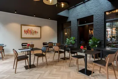 a restaurant with black tables and chairs and a brick wall at Vinotel X in Tongeren