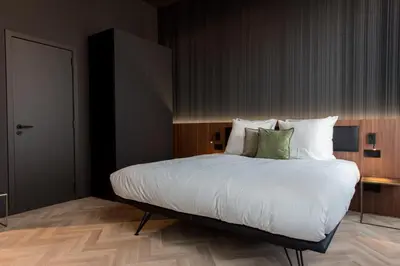 a bedroom with a large bed with white sheets and green pillows at Vinotel X in Tongeren