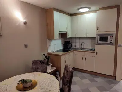 a kitchen with white cabinets and a table and a table and chairs at Your Stay in Kelmis - La Calamine- Cosy apartment in the Ardennes -Three-country point - Neu-Moresnet in Kelmis