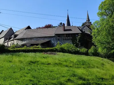 an old building on a grassy hill next to a church at Your Stay in Kelmis - La Calamine- Cosy apartment in the Ardennes -Three-country point - Neu-Moresnet in Kelmis