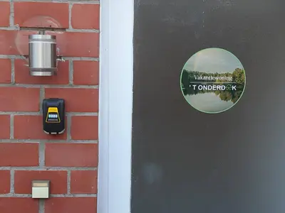 a door with a sticker on it next to a brick wall at 'T ONDERDAK in Lommel