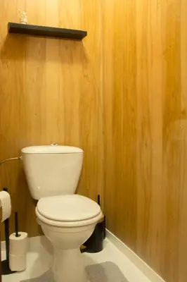 a bathroom with a white toilet in a wooden wall at 'T ONDERDAK in Lommel