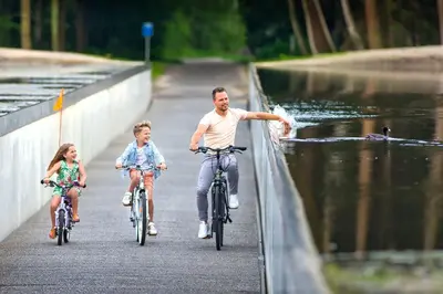 a man and two children riding bikes on a bridge at Factorij10 in Peer