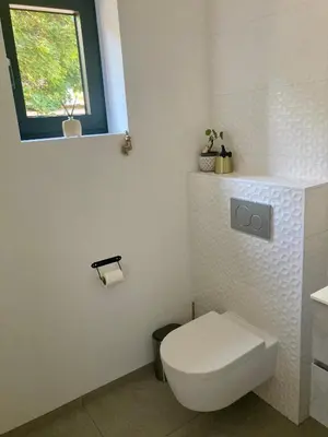 a white bathroom with a toilet and a window at B&B La Miniera in Genk