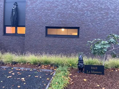 a black cat statue in front of a building at B&B La Miniera in Genk