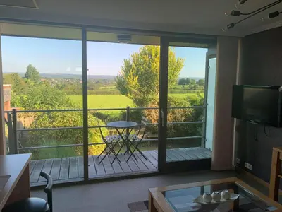 a room with a view of a balcony with a table at Le Petit Logis in Jalhay