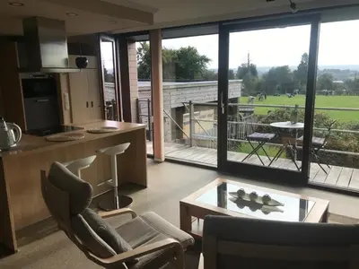 a living room with a kitchen and a large window at Le Petit Logis in Jalhay