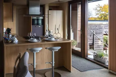 a kitchen with a counter with stools in it at Le Petit Logis in Jalhay