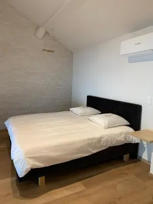a bedroom with a bed with white sheets and pillows at B&B elzartwinning in Hasselt