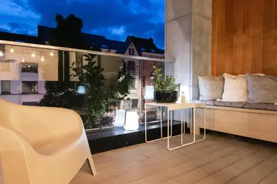 a balcony with a couch and a table and a window at Boulevard Botanie city apartment with parking in Hasselt