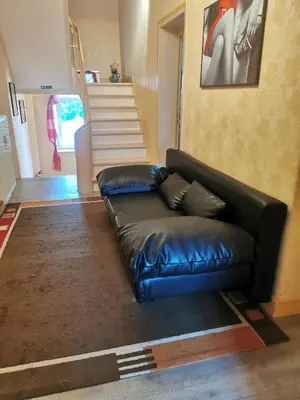 a black leather couch in a living room with stairs at Ferienwohnung in einem alten Bauernhaus in Lontzen
