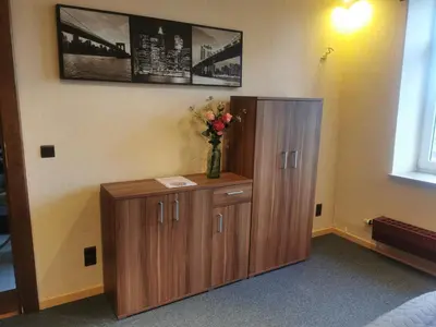 a wooden cabinet with a vase of flowers on it at Ferienwohnung in einem alten Bauernhaus in Lontzen